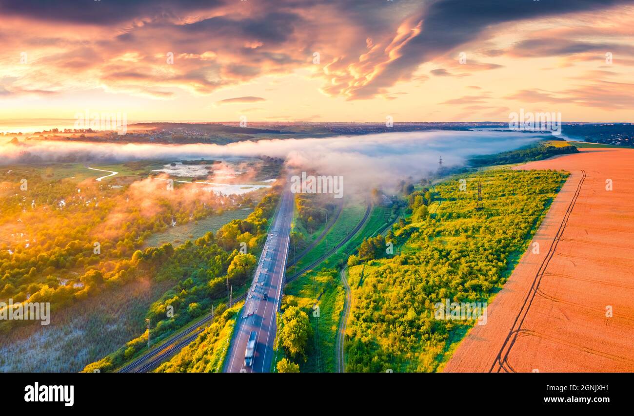 Fantastic summer sunrise on Ternopil outskirts with asphalt road. Aerial morning view of the Ukrainian countryside. Amazing landscape of field of whea Stock Photo