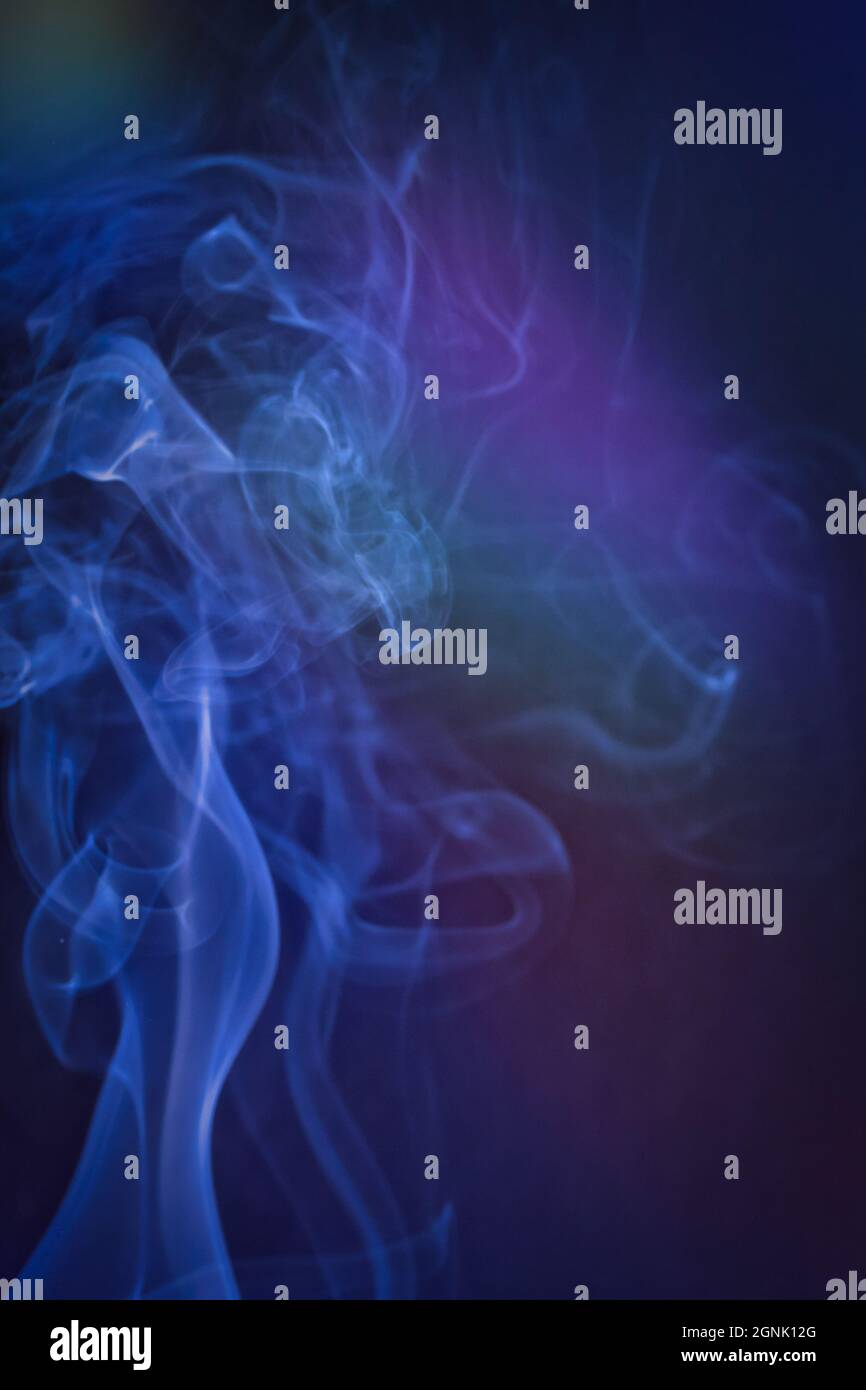 A vertical shot of smoke in colorfull backlight with a blue note Stock Photo