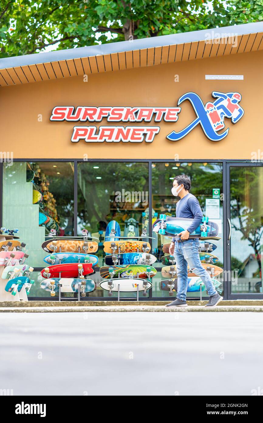 "Asian Cheerful man holding surfskate and walking in front of the