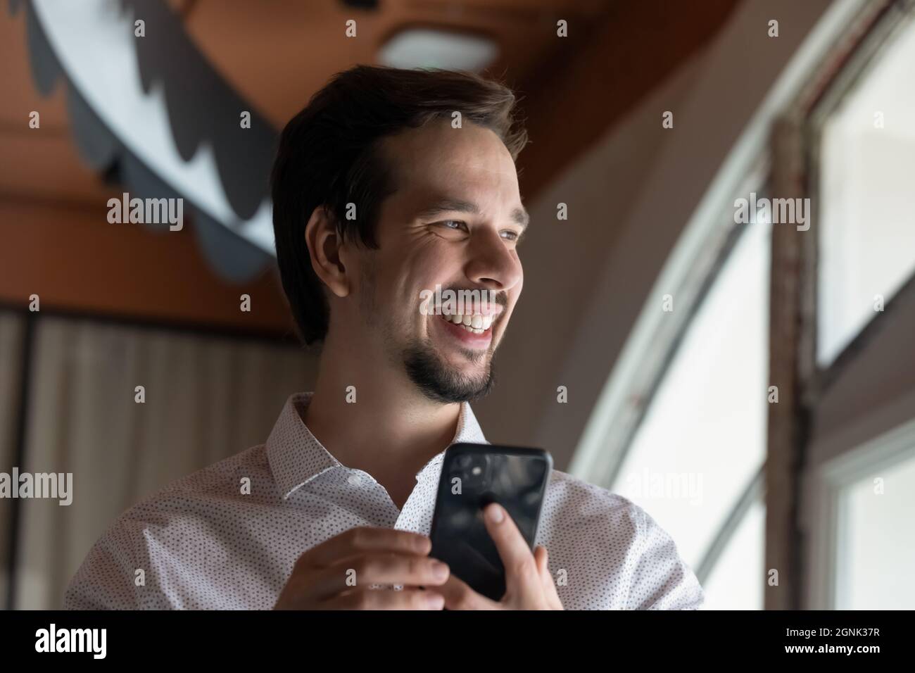 Happy millennial guy using smartphone, holding cell Stock Photo