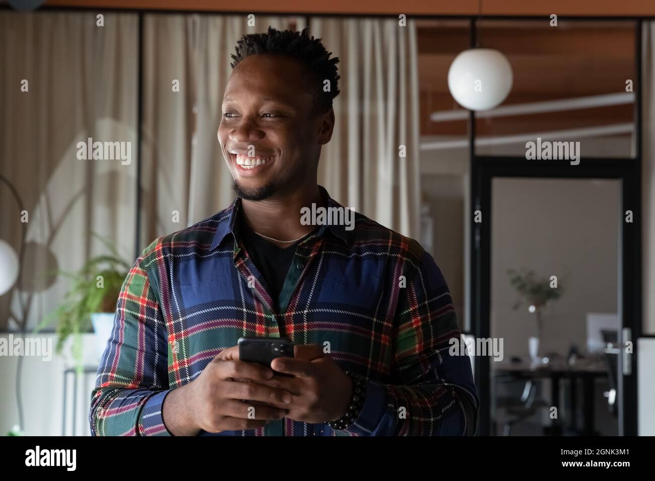 Happy millennial Black hipster employee holding mobile phone Stock Photo