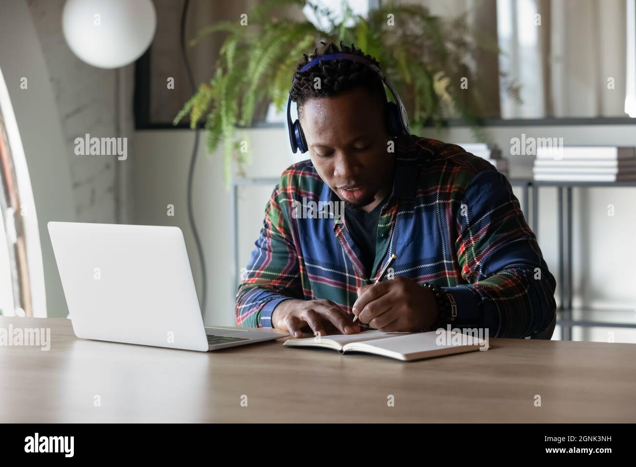 Focused serious African American student guy in headphones watching webinar Stock Photo