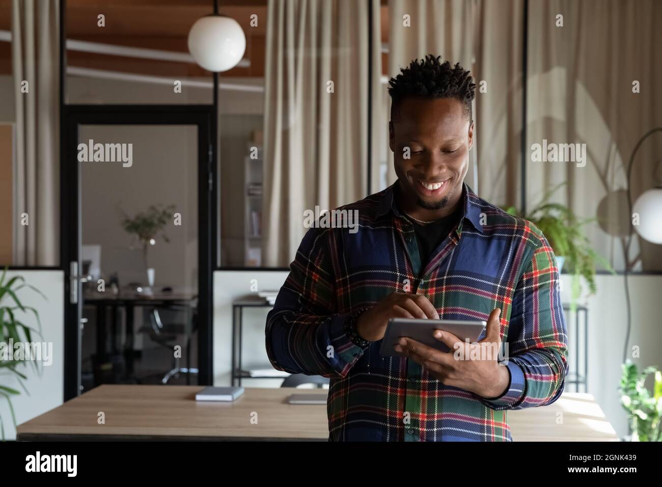 Happy millennial self employed professional using tablet in office Stock Photo