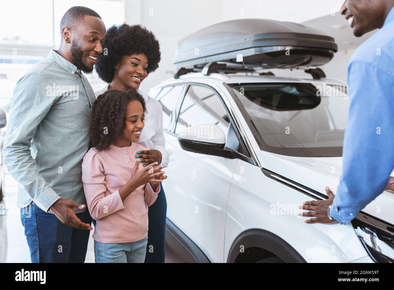 Automobile salesman demonstrating luxury car to millennial black family