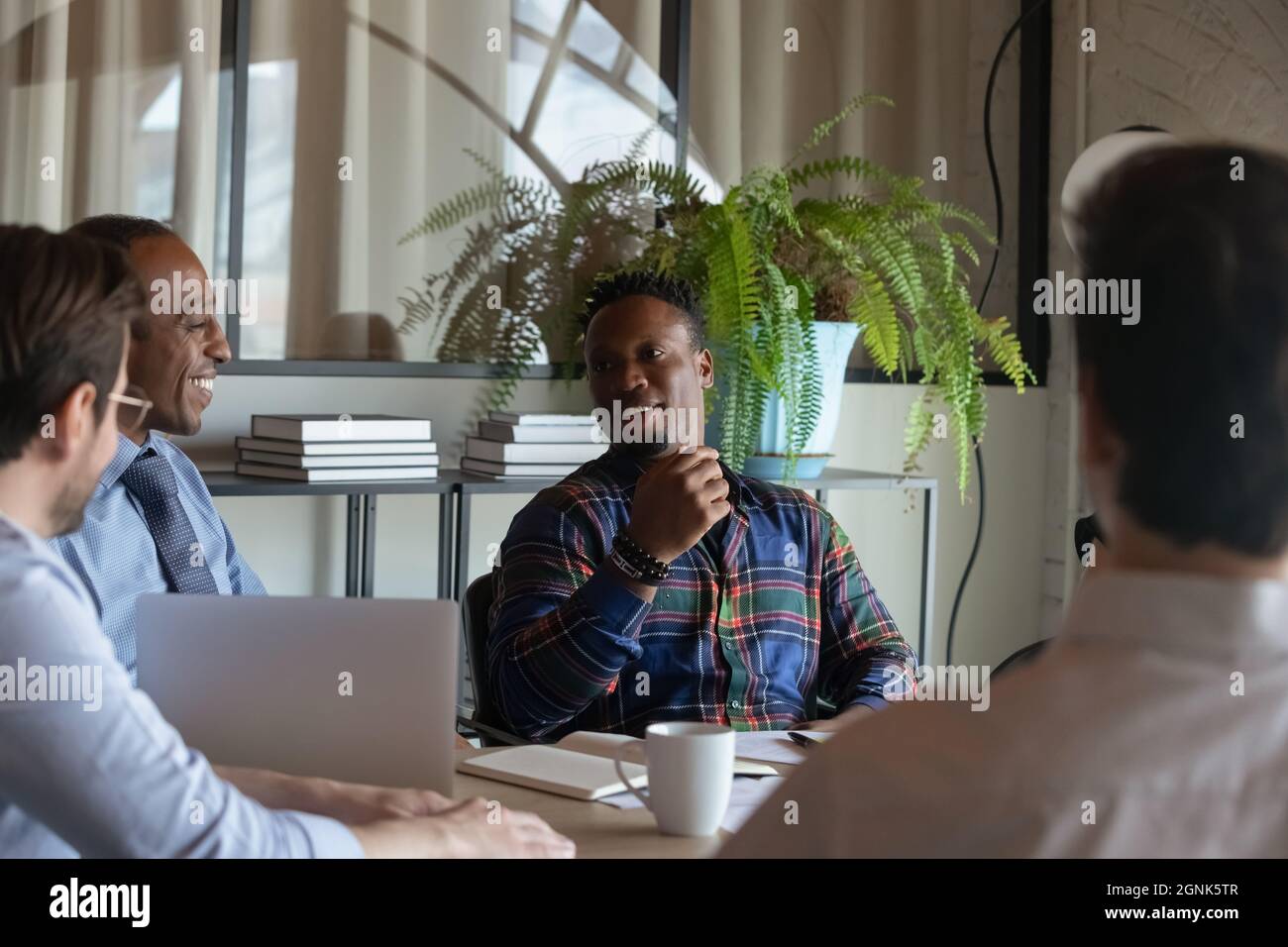 Happy African American hipster worker speaking on meeting, discussing project Stock Photo