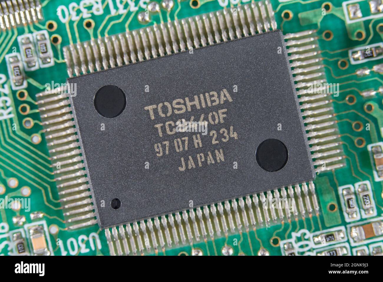 Gull-wing legs / pinouts of Toshiba integrated circuit / IC semiconductor on  green pcb circuit board. For electronics technology, world chip shortage Stock Photo