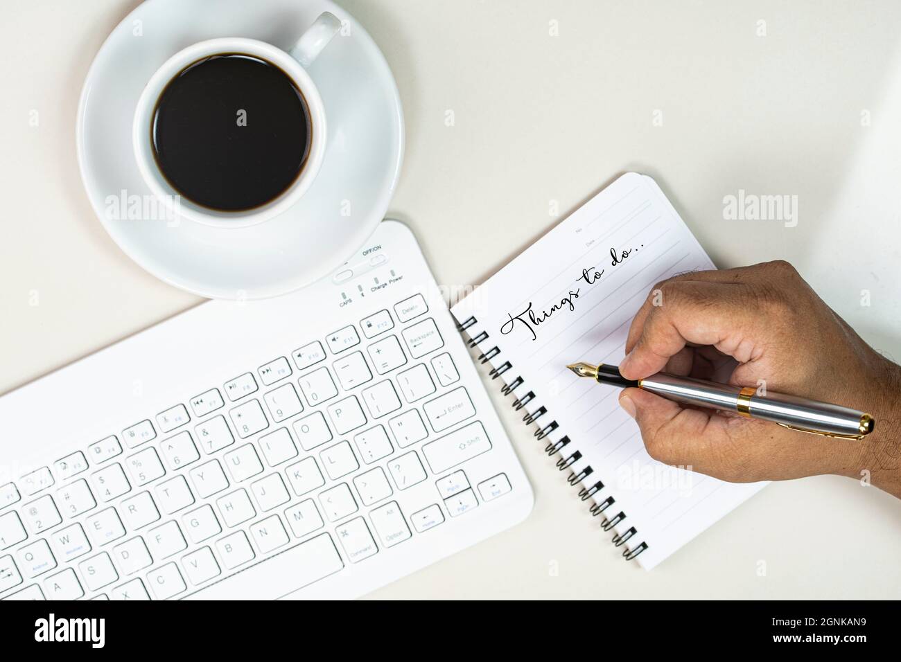 Working from home concept. Hand writing in a note book, keyboard and a cup of coffee. Selective focus points Stock Photo