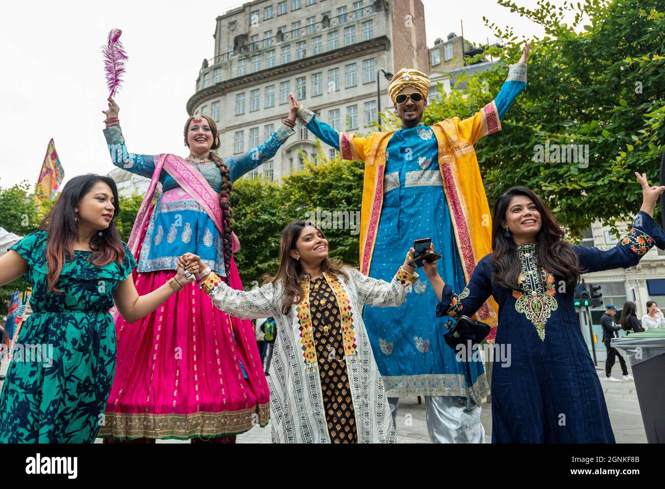 London, UK. 26th Sep, 2021. Costumed stilt walkers and people taking