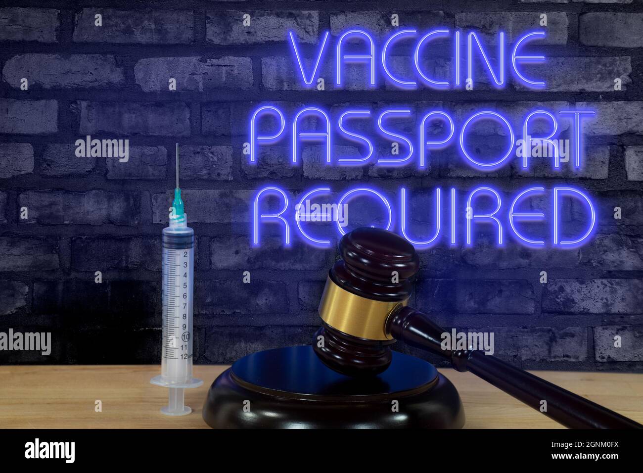 Wooden court gavel and a vaccination syringe with glowing purple neon sign on brick wall Stock Photo