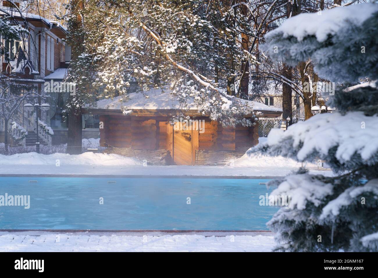 Winter wellness spa resort center with outdoor swimming pool of thermal water stream in frozen air Stock Photo