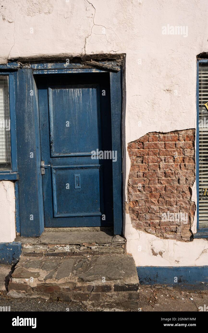 Weathered blue door and crumbling render on old Welsh building Stock Photo