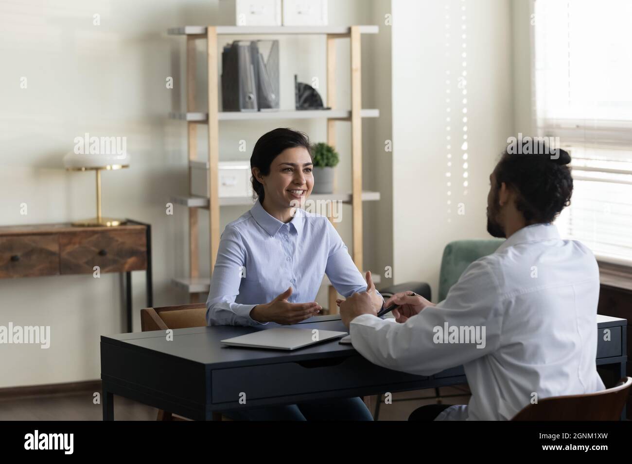 Happy Indian woman consulting young male doctor at appointment Stock Photo