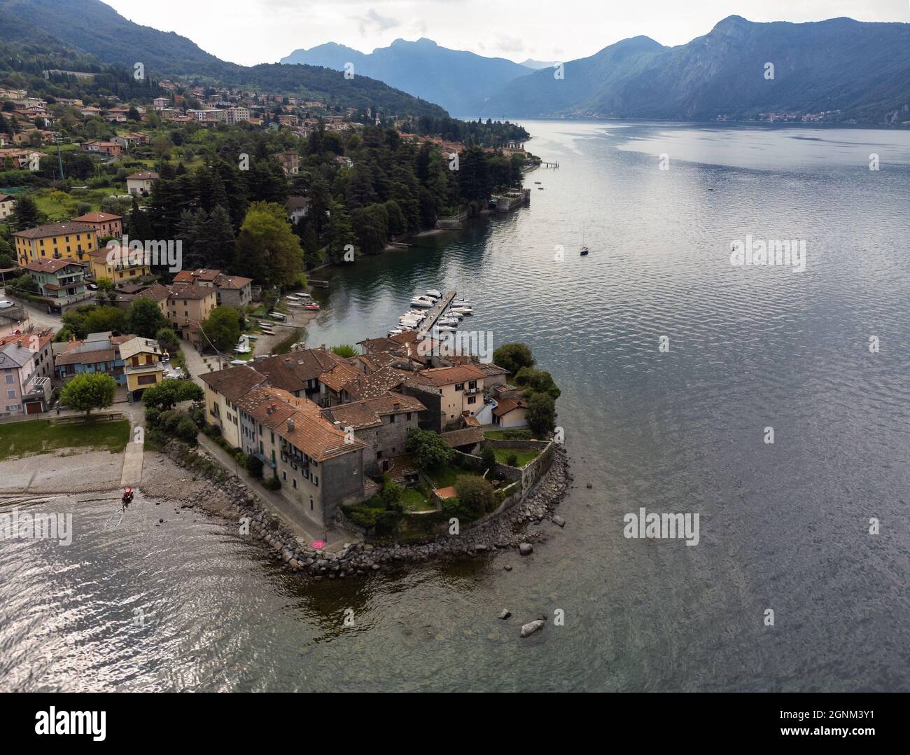 Small village located on a peninsula of Lake Como next to a marina with moored boats - Aerial View,  Lierna, Lombardy, Italy Stock Photo