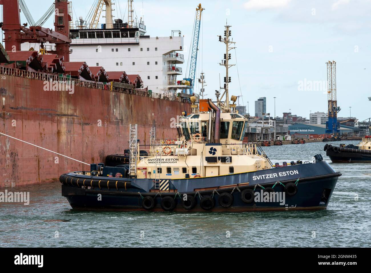 Southampton, England, UK. 2021. An ocean going tug manoeuvres a bulk carrier ship onto her berth in the port of Southampton. Stock Photo