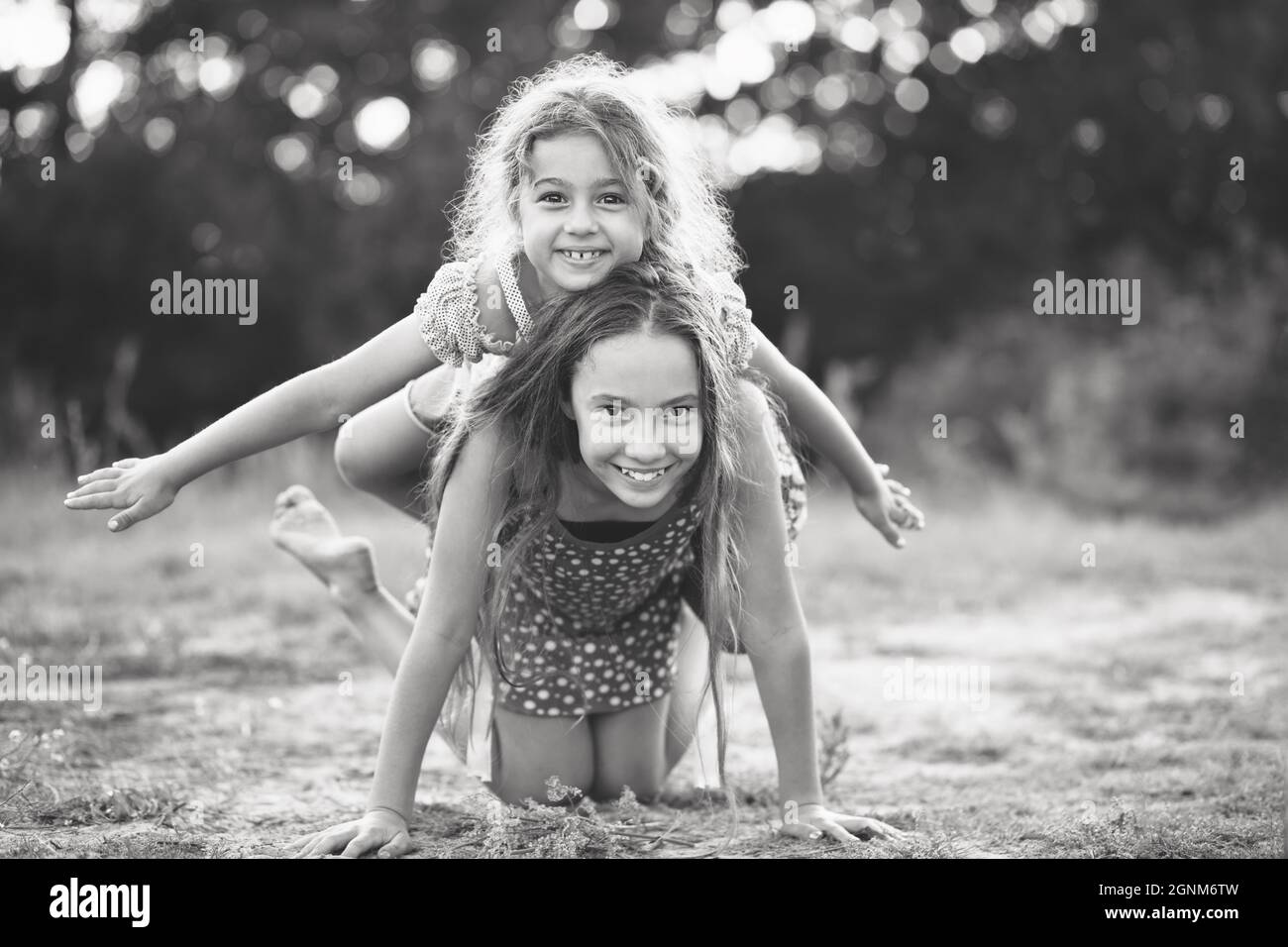 Black and white portrait of Two Cute little girls playing and laughing at the countryside. Happy kids outdoors concept Stock Photo