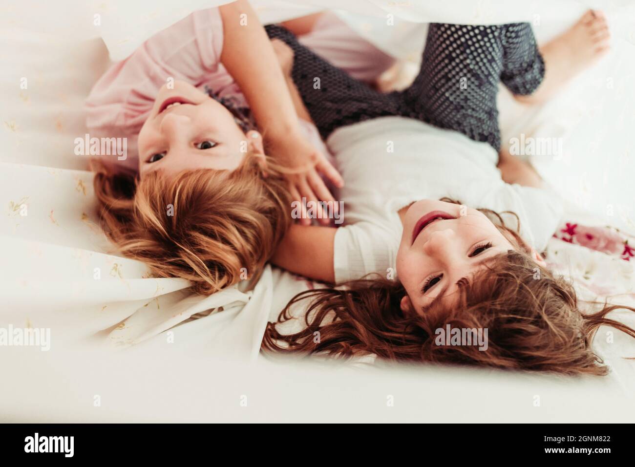 Cute little girls, sisters waking up in the morning. Kids in pajamas, sleeping, girls room Stock Photo