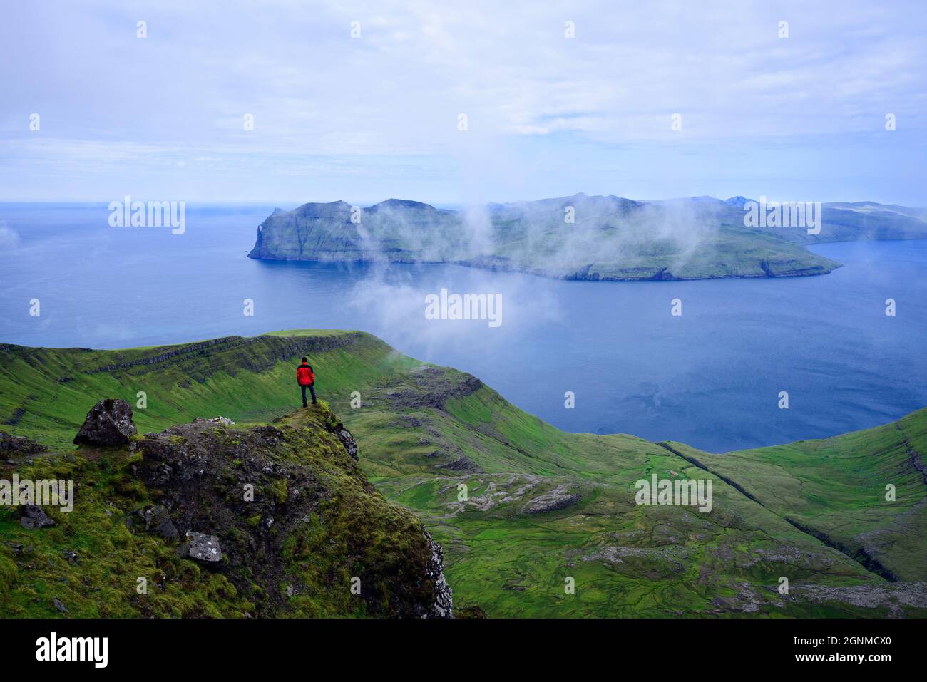 Tourist enjoying the view of Vagar Island from Mount Sornfelli on Streymoy island in the Faroe Islands Stock Photo