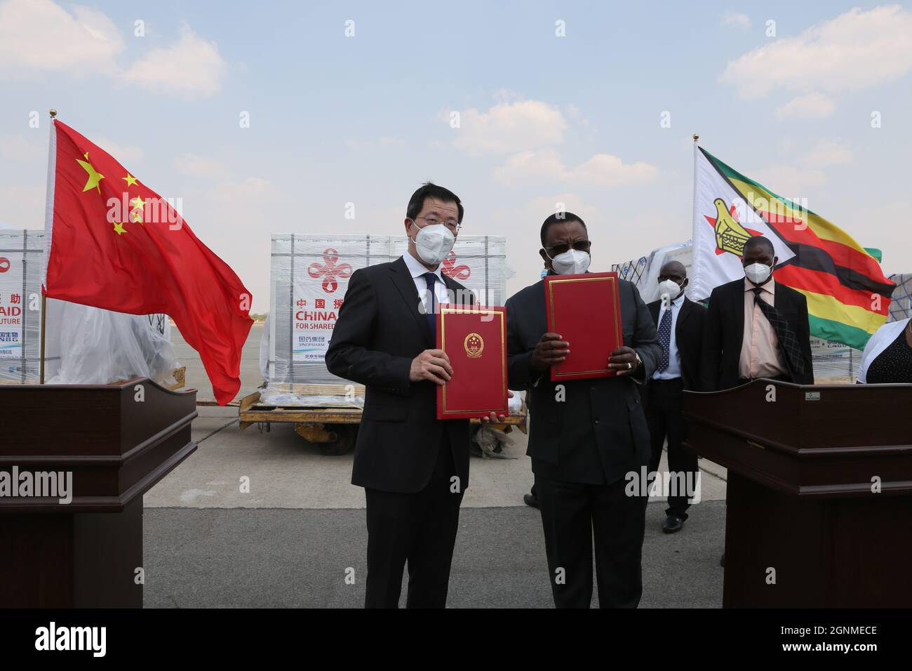 Harare, Zimbabwe. 26th Sep, 2021. Chinese Ambassador to Zimbabwe Guo Shaochun (L, front) and Zimbabwean Vice President Constantino Chiwenga (R, front), who is also the country's minister of Health and Child Care, pose for a photo during a handover ceremony of China-donated vaccines at Robert Gabriel Mugabe International Airport in Harare, Zimbabwe, on Sept. 26, 2021. Zimbabwe on Sunday received the fourth batch of Sinopharm COVID-19 vaccine doses from China. Credit: Chen Yaqin/Xinhua/Alamy Live News Stock Photo