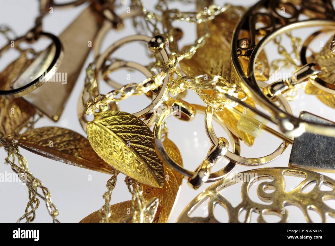 close up macro of a pile of tangled up gold colored alloyed jewelry on a white background with a shallow depth of field Stock Photo