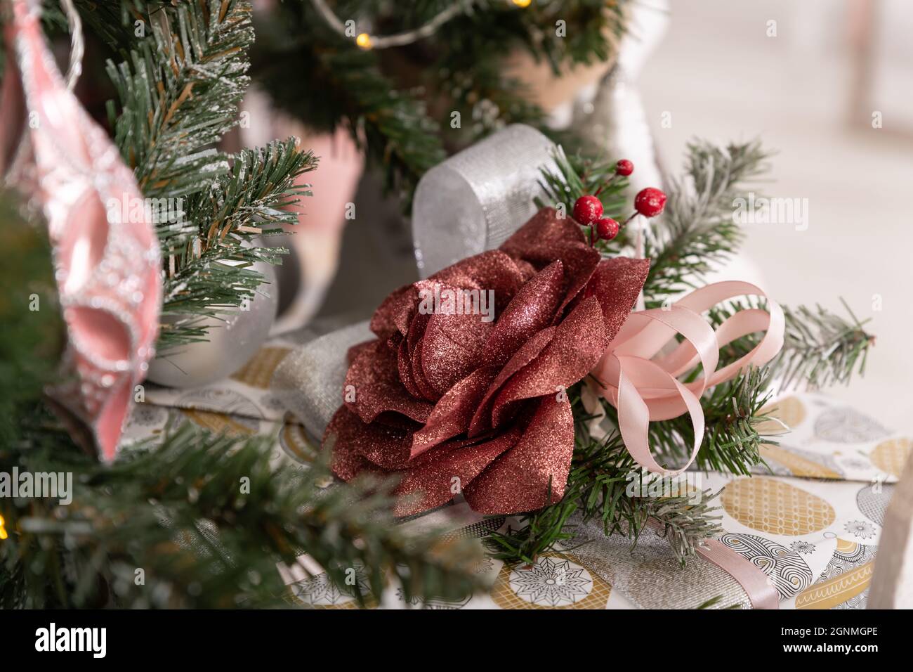 Christmas decorated tree in soft pink colors against the background of white classic fireplace with Christmas decorations. Details of New Year festive Stock Photo