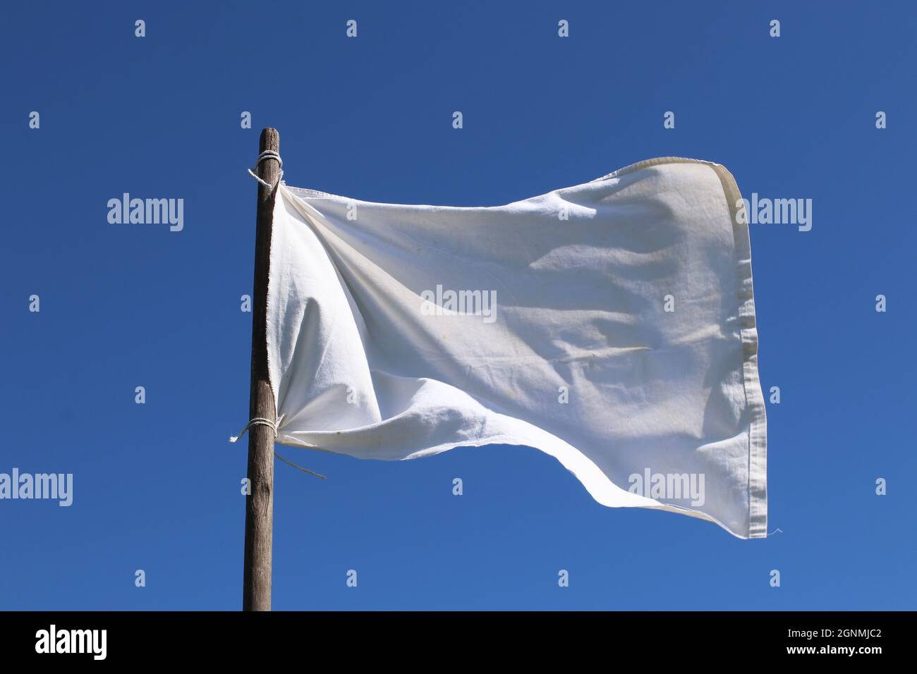 The white flag against the blue sky.  Surrender concept. Stock Photo