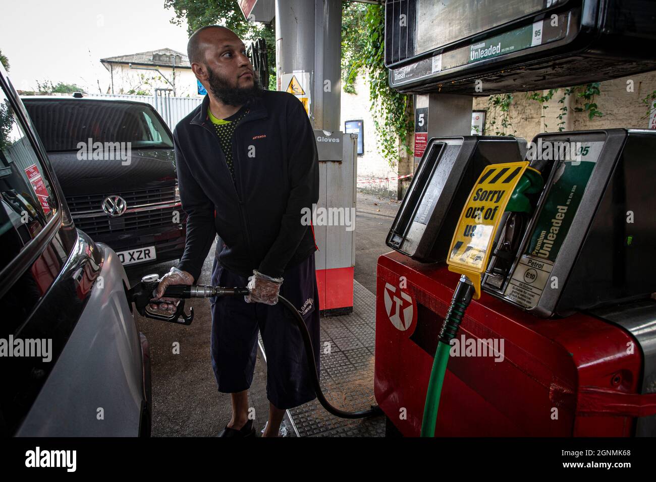 Cab driver is fill tank next to out of use sign on petrol pumps without fuel at petrol station in London , United Kingdom Stock Photo