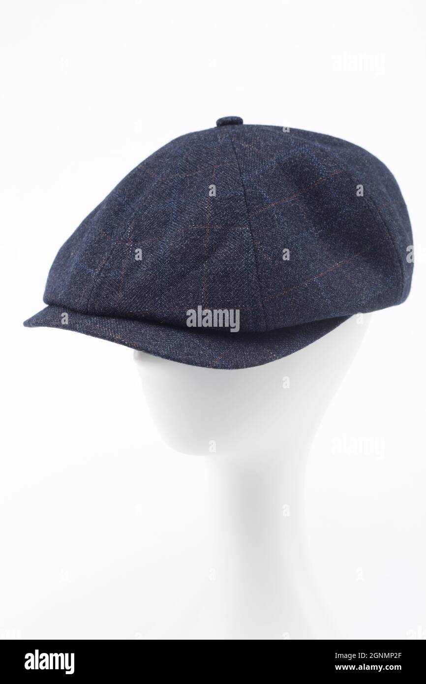 A dark blue checkered peaked cap with a visor on the head of a white mannequin. Blue checkered peaked cap isolated over white background. Stock Photo