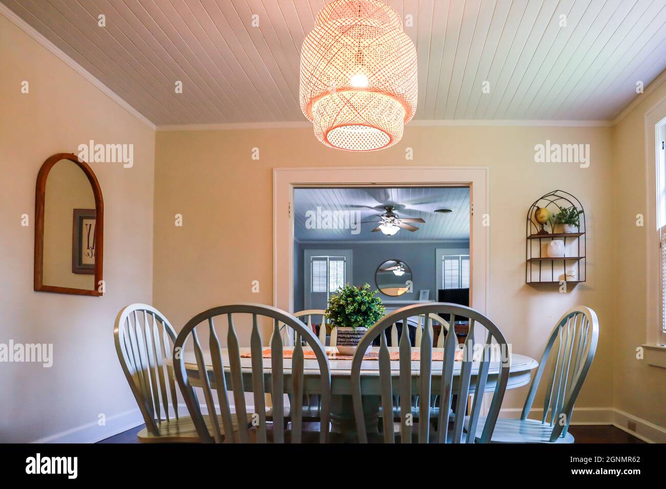 A small dining room with a statement rattan lighting ficture and a