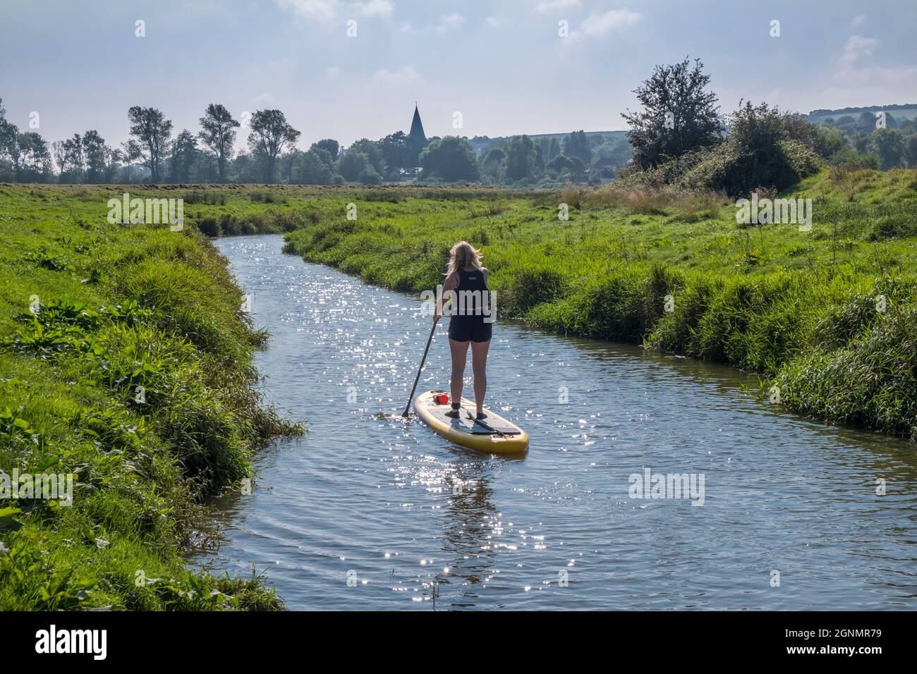 Paddle boarder on the River Cuckmere going downstream to Alfriston. Alfriston, E Sussex, UK. Stock Photo