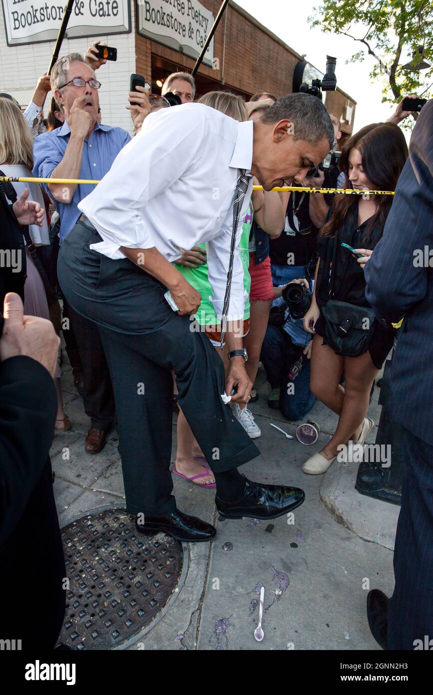 President Barack Obama wipes off his trousers after being splattered by frozen yoghurt outside the Sink Restaurant & Bar in Boulder, Colo., April 24, 2021. University of Colorado freshman Kolbi Zerbest, right, had placed the cup on the ground while trying to shake hands with the President, and someone inadvertently kicked the cup. (Official White House Photo by Pete Souza) This official White House photograph is being made available only for publication by news organizations and/or for personal use printing by the subject(s) of the photograph. The photograph may not be manipulated in any way a Stock Photo