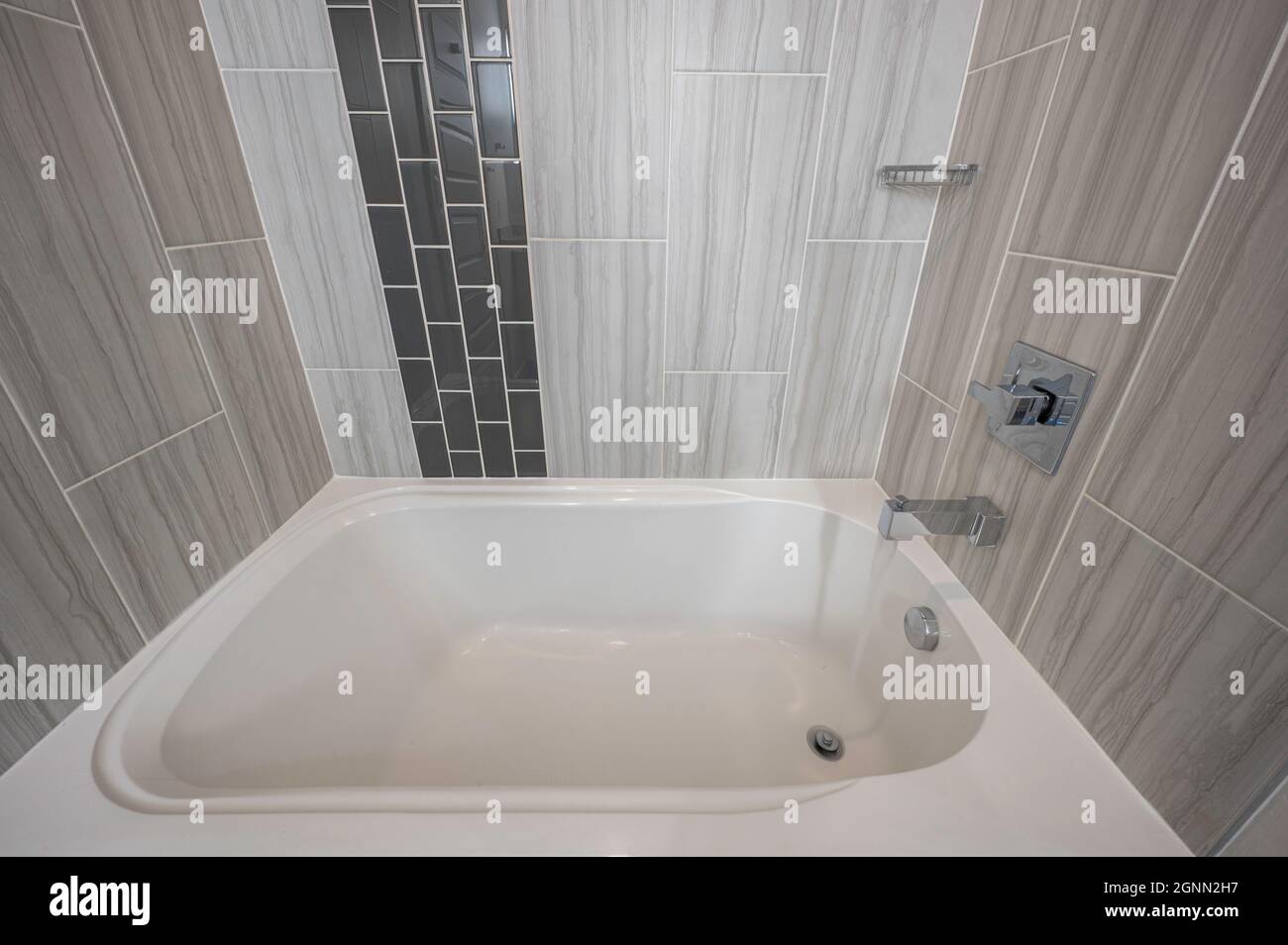 Modern bath tub with tiled backsplash and water running Stock Photo Alamy