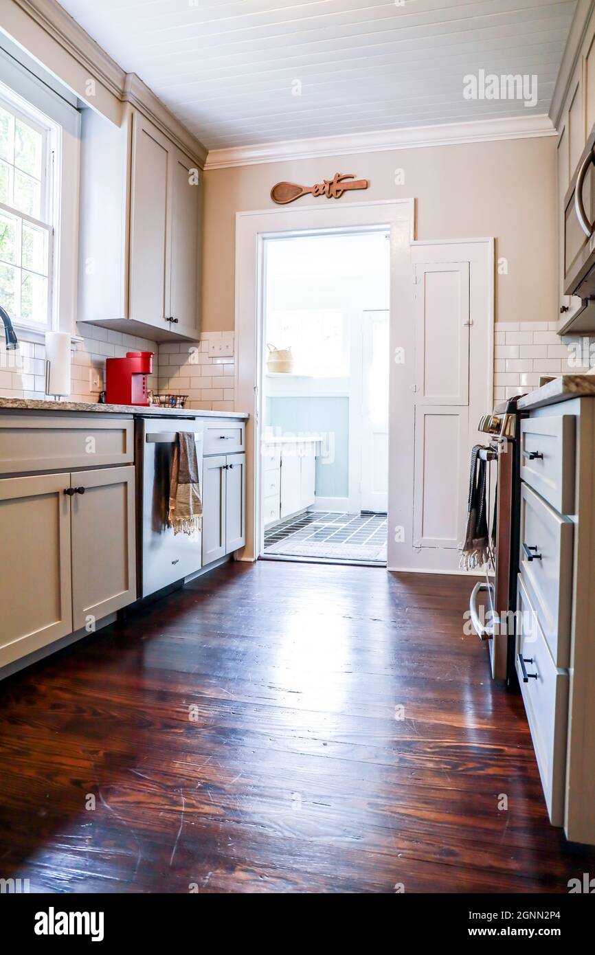 A small cottage kitchen with gray cabinets and dark hardwood floors in a short-term rental house Stock Photo