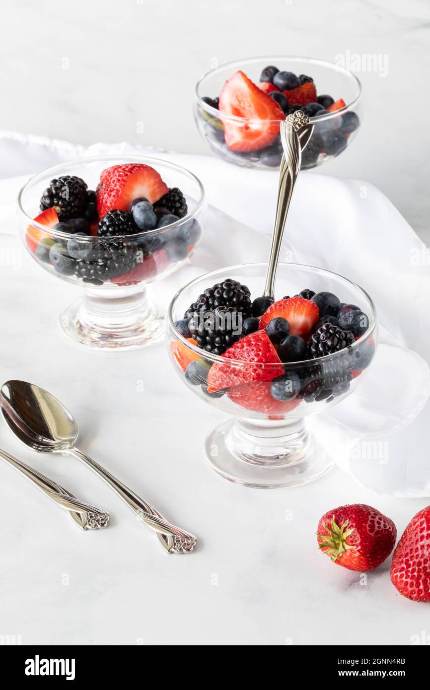 Glass dishes of mixed berries against a white background. Stock Photo