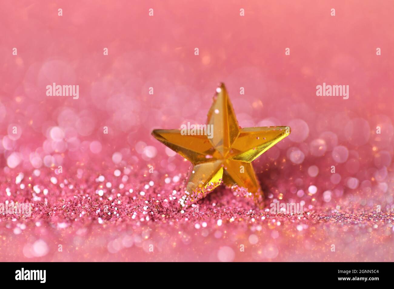 Wallpaper shining glitter.New Year and Christmas background. gold star in pink glitter on shining background.Beautiful festive background in rose gold Stock Photo