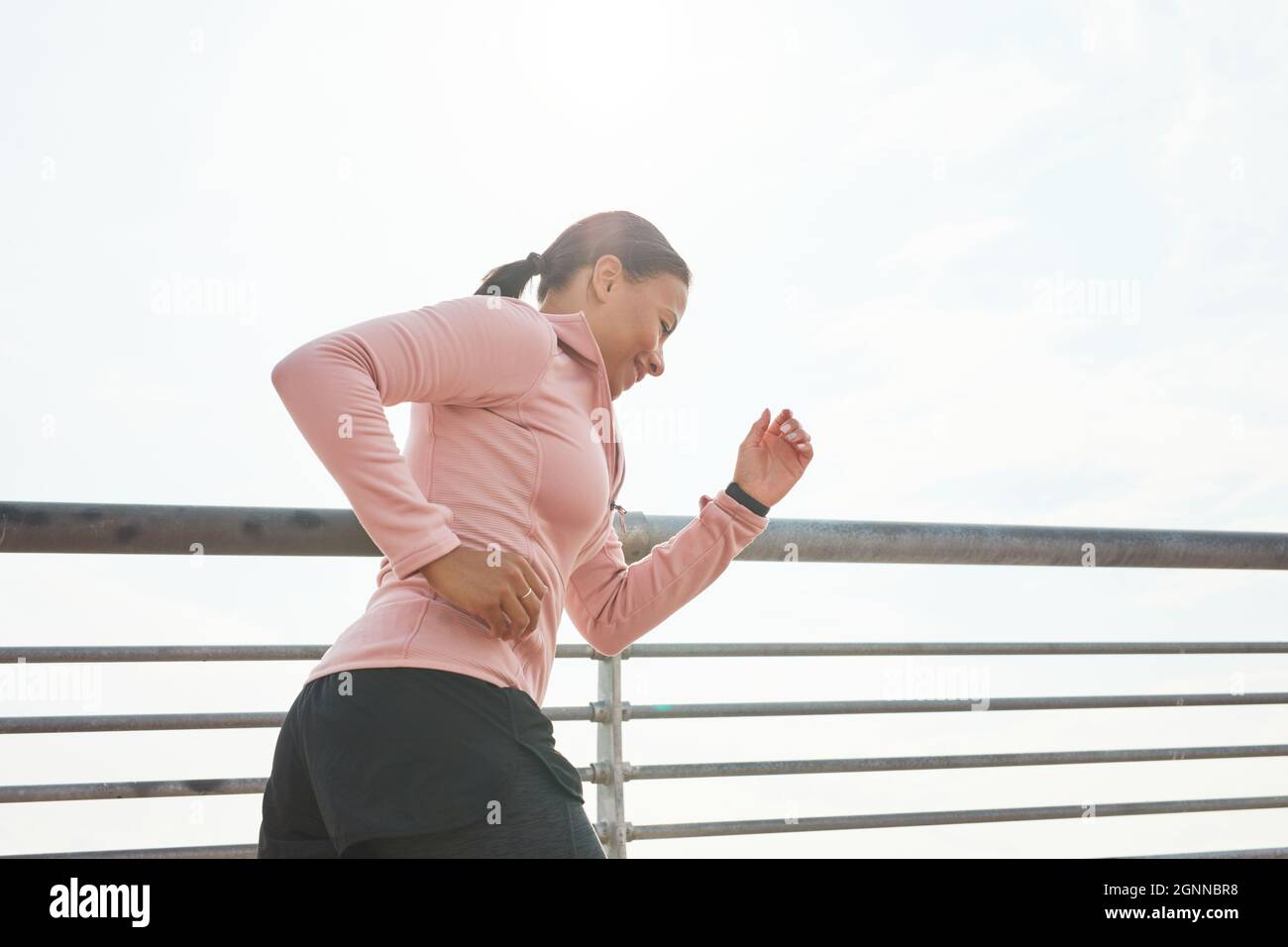 Young woman in sports clothing running in the morning outdoors Stock Photo