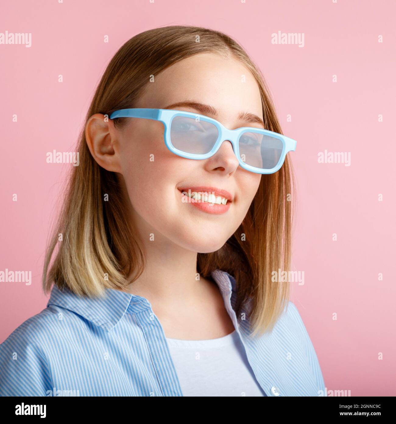 Smiling teenager girl portrait movie viewer in glasses isolated over pink color background with copy space. Young woman in cinema glasses for watching Stock Photo