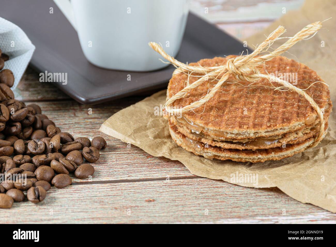 closeup of stroopwafel biscuits with a sisal bow next to coffee beans. Stock Photo