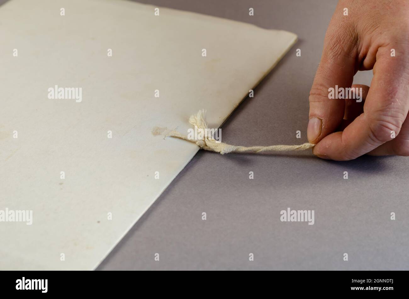 Mature male hand tugging at the tie on a file folder. Person unt Stock Photo