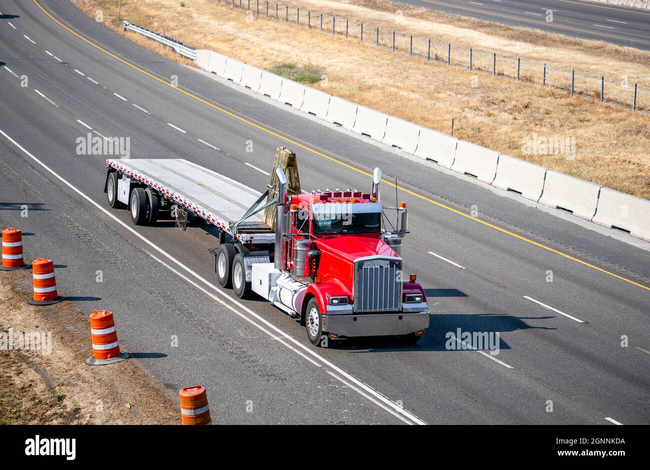 Classic red semi truck with additional side lights and tall chrome exhaust pipes