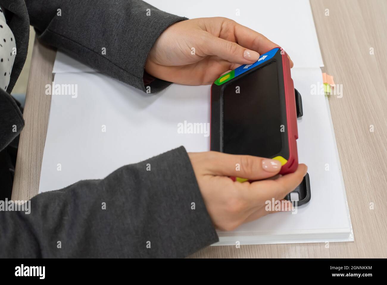 The woman is holding a reading device for the visually impaired