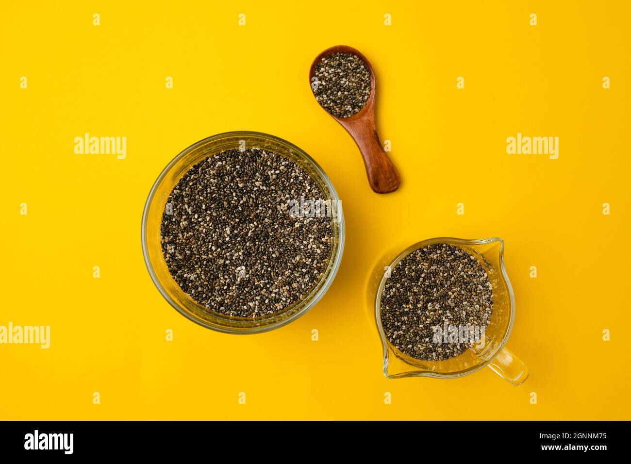 Glass bowl and spoon with chia seed son a bright yellow background with copy space, closeup, view from above Stock Photo