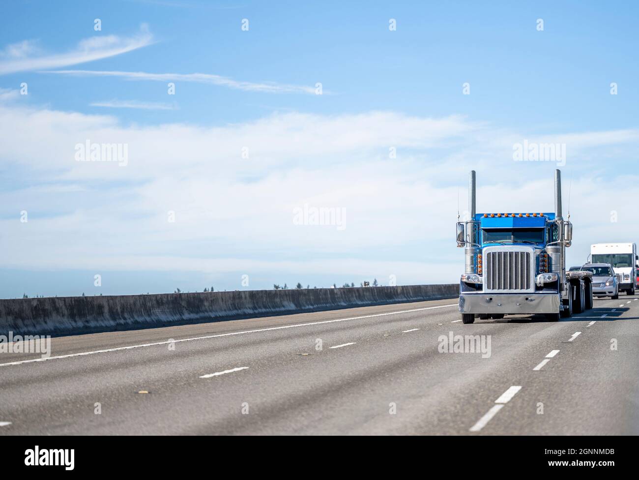 Classic old style blue semi truck with additional side lights and tall chrome exhaust