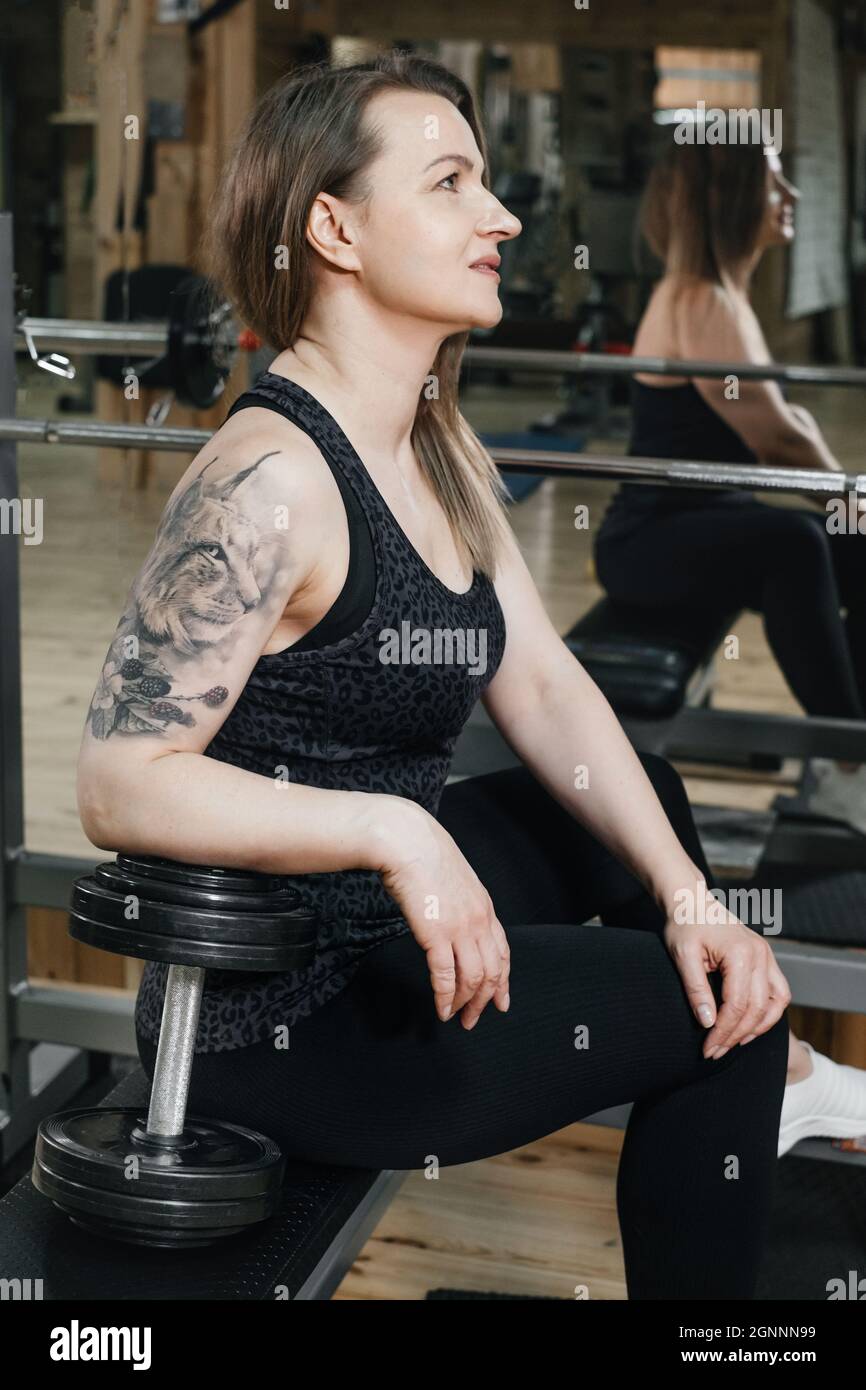 Sporty Strong and fit woman in Gym, warming up. Middle aged woman powerlifter with tattoo