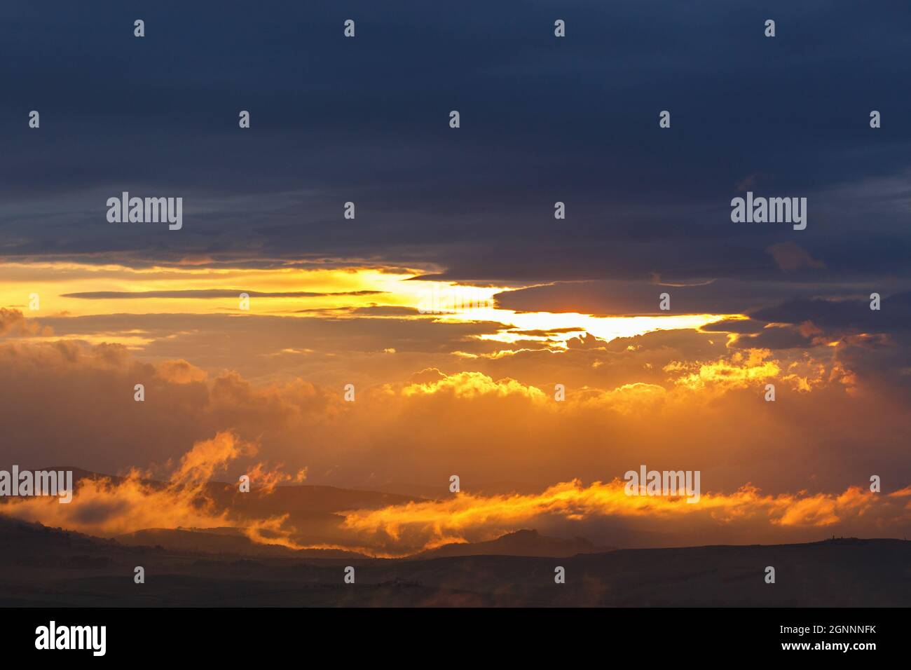 Low clouds in backlight over a landscape at sunset Stock Photo