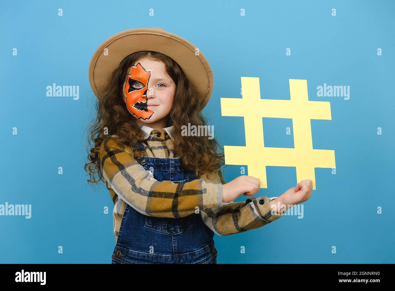 Adorable little girl child with Halloween mask holding yellow hashtag