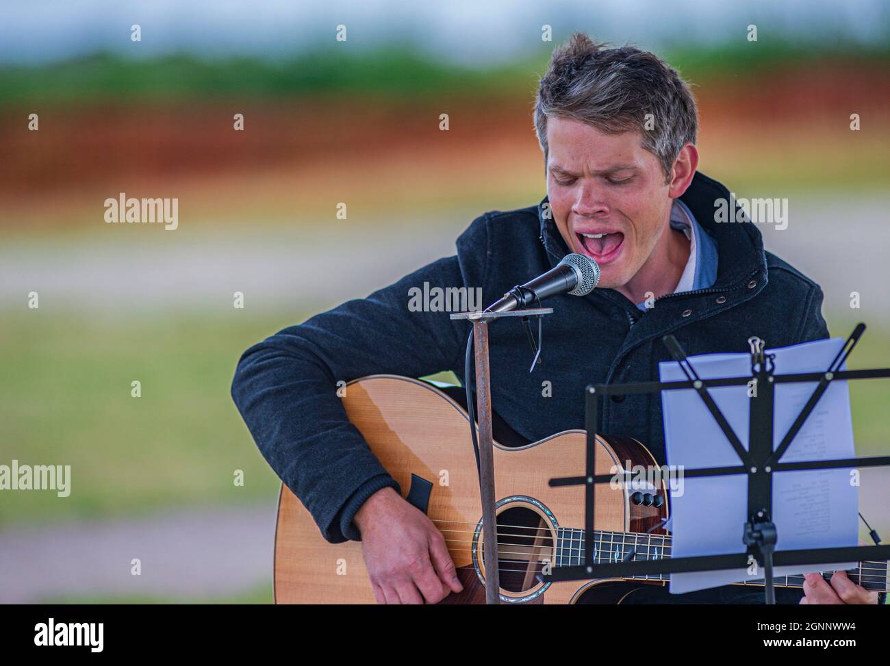 A guitarist and folk singer performing at an outdoor event Stock Photo