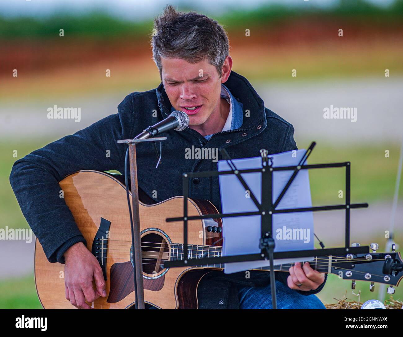 A guitarist and folk singer performing at an outdoor event Stock Photo