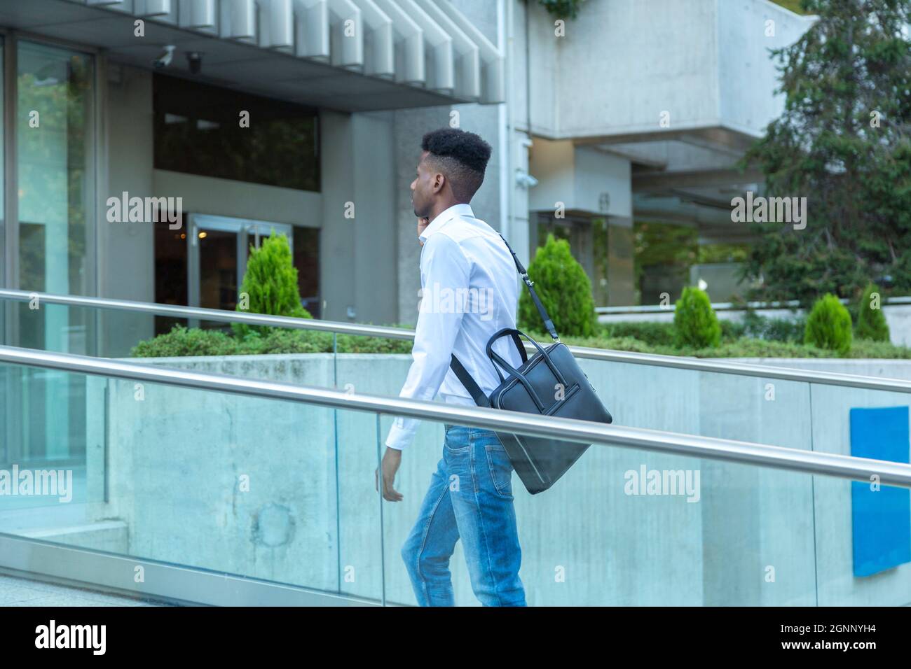 young black business man walking on a glass bridge connected by phone Stock Photo
