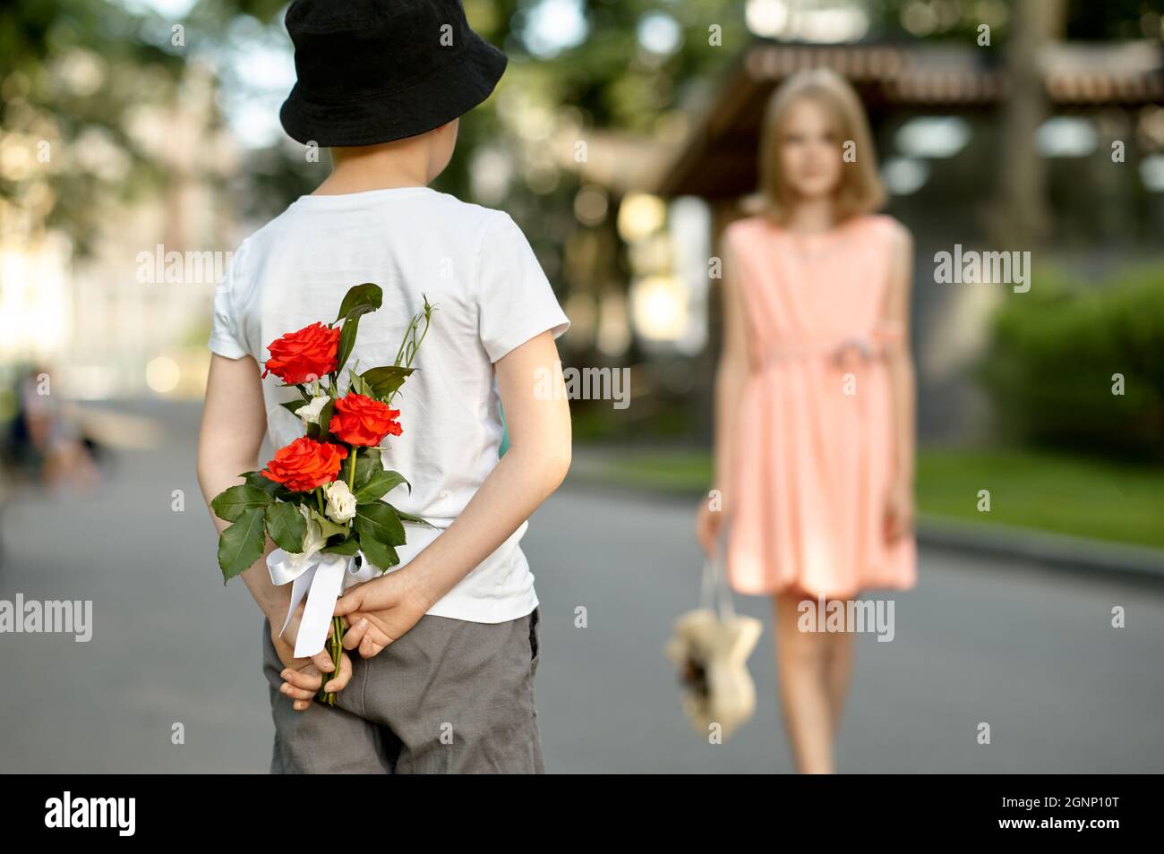Children's date, boy hides flowers from a girl Stock Photo