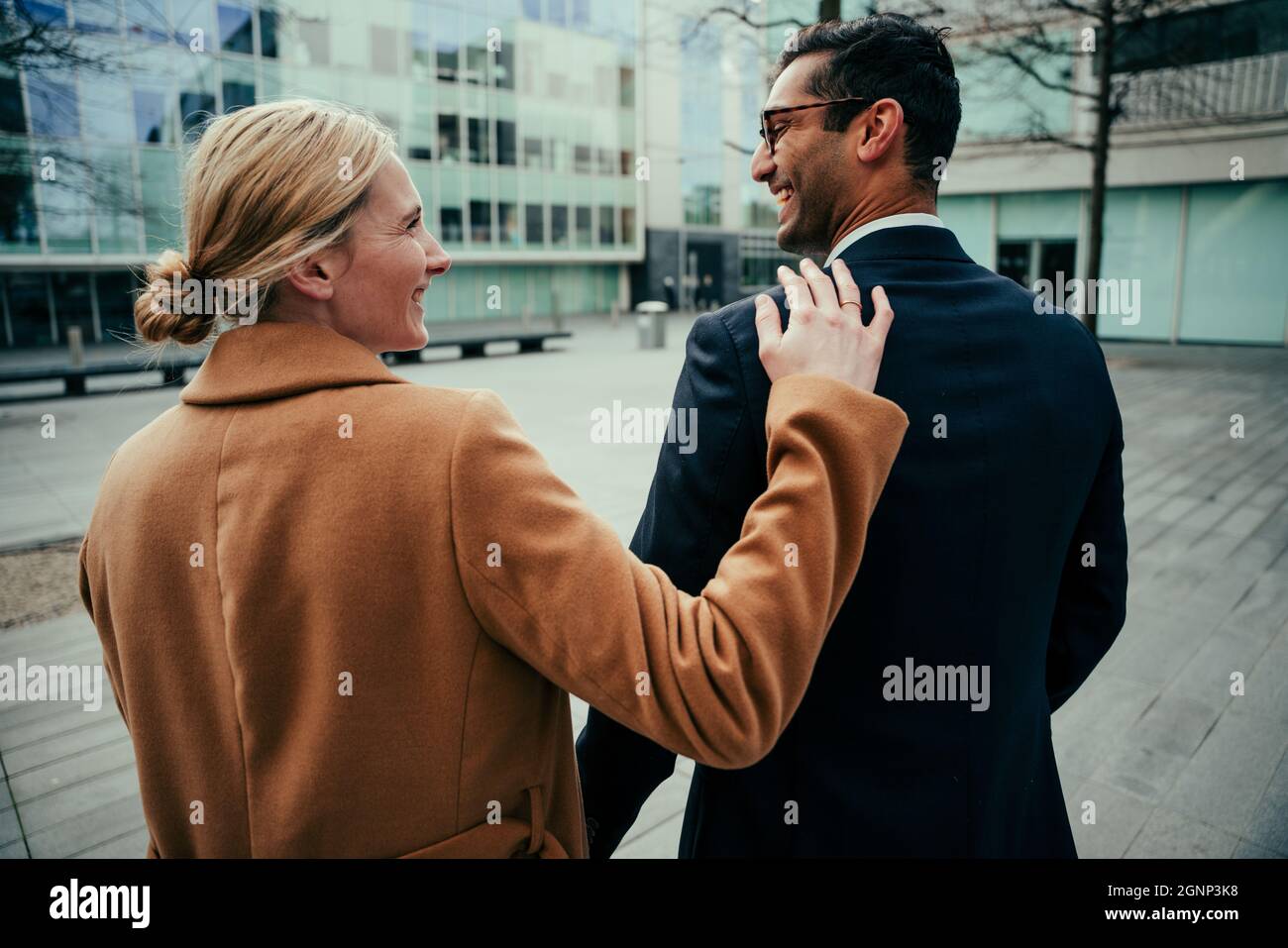 Caucasian business man and woman walking through city smiling at ...